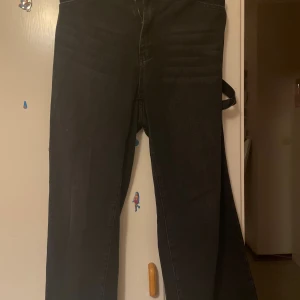 Svarta cargopants med breda ben - Säljer ett par svarta cargopants med breda ben och stora bakfickor. Byxorna har en cool utility-look med sidoficka och klassiska sömmar. Materialet är jeans och passformen är loose, perfekt för en avslappnad streetstil. Och jag har använt den en gång de va fint men sen såg jag att den passar inte in min stil 