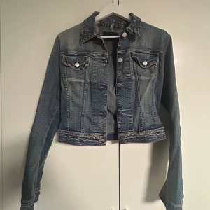 Blå croppad jeansjacka Les Copains - Snygg lite croppad jeansjacka från Les Copains Jeans i klassisk blå denim med kontrastsömmar i rosa. Det står inte någon storlek i jackan men skulle säga att den passar xs/s. 