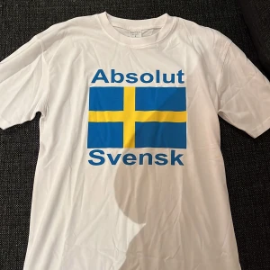 Absolut svensk T-shirt  - Vit ”absolut svensk” T-shirt, storlek S. Skick 10/10 (aldrig använd) inte ens testad. Perfekt för dig som vill visa stolthet för Sverige. Den ser skrynklig ut för den bara legat i en påse. Pris kan diskuteras (först till kvarn)