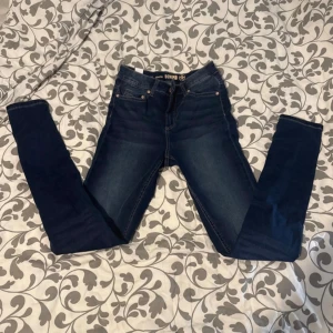 Mörkblå Stella Denim jeans, storlek 36 - Snygga mörkblå jeans från Stella Denim i storlek 36. Modellen har klassisk femficksdesign, kopparfärgade nitar och kontrastsömmar. Jeansen är raka och har en normal passform med midwaist. Perfekta för dig som gillar stilrena och tidlösa jeans.