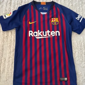FC Barcelona matchtröja Nike M - Säljer en officiell FC Barcelona matchtröja från Nike med Dri-FIT-material. Tröjan är blå och röd med smala vertikala ränder, klubbmärke på bröstet, La Liga-märke på ärmen och Rakuten-tryck framtill. Perfekt för dig som älskar Barca!