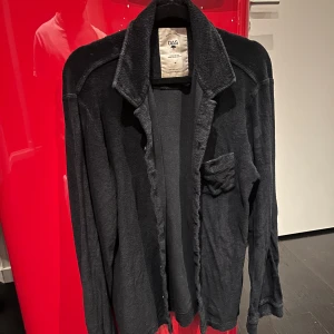 Svart frottéskjorta från OAS - Svart skjorta från OAS i mjuk frotté-bomull, perfekt att dra på sig efter badet. Skjortan har klassisk krage, lång ärm och en bröstficka. Snygg loose fit och enkel design som ger chill vibe.