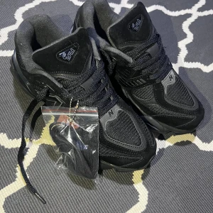 New Balance 9060 svarta sneakers - 👟 New Balance 9060 Triple Black – Storlek 42 (26 cm)  Skorna är begagnade men i mycket fint skick – ser fortfarande nästan nya ut. Inga slitningar, inga fläckar och inga skador. Endast använda ett fåtal gånger. Kommer med extra svarta skosnören (oanvända) ✅  Detaljer: • Modell: New Balance 9060 • Färg: Triple Black 🖤 • Storlek: 42 EU (26 cm / US 8.5) • Bekväma och lätta att matcha • Fräscha insidor och sulor, bra skick  Perfekta till både vardag och gym. Riktigt snygg siluett och populär modell 