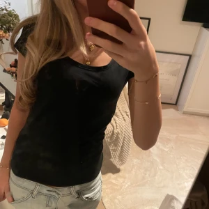 Svart tight kortärmad topp - Säljer en svart, enkel och stilren topp med rund halsringning och korta ärmar. Modellen är tight och sitter snyggt mot kroppen, perfekt att matcha med jeans eller kjol. Materialet känns mjukt och bekvämt mot huden.