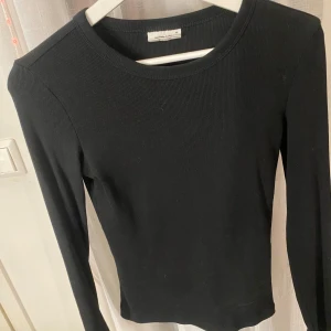 Svart ribbad långärmad tröja XS - En svart, ribbad långärmad tröja från Gina Tricot. Tröjan har en rund halsringning och är figurnära i modellen. Knappt använd så den är i mycket bra skick