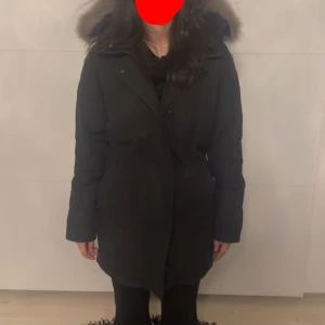 Svart parka från Canada Goose  - Svart parka från Canada Goose med modellen. Jackan är i mycket bra skick överlag, men den nedre dragkedjan har lossnat. Därför kan priset diskuteras vid ett rimligt bud. I övrigt är jackan välvårdad, ren och redo att användas. Perfekt för dig som vill ha en kvalitetsjacka till ett bra pris!