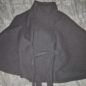 Poncho Kappa/Jacka! - En superfin poncho jacka/kappa från Gina Tricot! Storlek 9-11 år men passar mig som är 16 år. Använd men riktigt fint skick! Hittar inga defekter. Lågt pris då den är köpt med Rabatt, nypris 450:-. Min har dock ingen sån guldknapp, tror inte det fanns en när den köptes så kan vara borta eller så e de en liknande bara! Sömmen från etiketten syns dock utanpå nacken på utsidan, tror det ska vara så dock. Katt finns I hemmet och kan förekomma hår! 🥰❤️ Prisförslag välkomna!