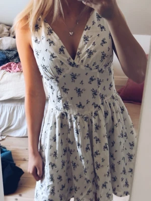 Vit blommig kortklänning med v-ringning - Supersöt vit kortklänning med små svarta blommor och v-ringning