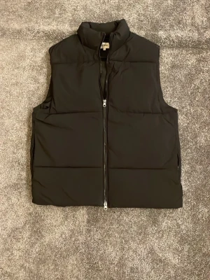 Svart dunväst från East West M - Säljer en svart dunväst från East west i mycket bra skick. Den är inte så använd och finns inga täcken på användning. Säljer den billigt då jag vill bli av med kläder från garderoben just nu.   KOLLA IN MIN PROFIL FÖR KLÄDER TILL ETT BARNSLIGT PRIS 🏆 