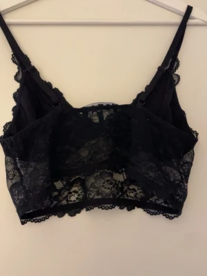 Svart spetsig linnetopp från I STAY - Säljer en svart linnetopp från I STAY i storlek M. Toppen har justerbara smala axelband och är helt täckt av blommig spets med transparenta detaljer. Den är croppad och har en feminin look med fina spetskanter längs hela toppen.