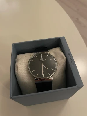 Skagen klocka svart - Bilderna visar en klocka från Skagen med svart läderarmband och stilren urtavla, aldrig använd, kommer i originalförpackning, inte hugget i sten🤝Nypris: 1500kr, mitt pris 700kr