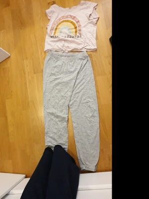 Grå mjukisbyxor från KappAhl stl 146/152 - Ett par ljusgrå mjukisbyxor från KappAhl i storlek 146/152. Byxorna har resår i midjan och är tillverkade i mjukt bomullsmaterial, perfekta för chill dagar hemma eller till träning. Klassisk rak passform och enkel design.