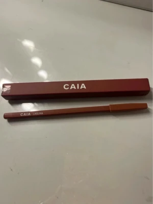 CAIA Laguna läppenna  - Snygg läppenna från CAIA i färgen Laguna. Pennan har en brunröd ton och kommer i en stilren, matchande förpackning. Perfekt för att definiera och forma läpparna med ett mjukt resultat. Pennan är i trä med plastlock.