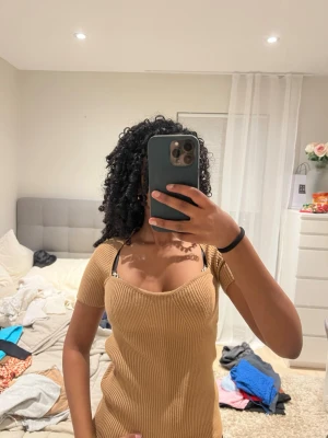 Beige ribbad topp med sweetheart-ringning - Säljer en beige ribbad topp från NA-KD med snygg sweetheart-ringning och korta ärmar. Toppen är figurnära och har en stretchig passform som framhäver siluetten. Perfekt att styla med jeans eller kjol för en trendig look.