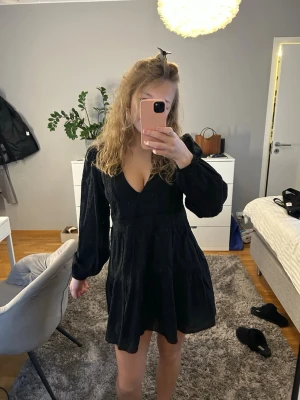 Svart klänning från Zara - Supersnygg svart klänning från Zara i storlek S med v-ringad hals och långa puffärmar. Klänningen har en lätt volang nedtill och är i toppen skick. Endast använd en gång.