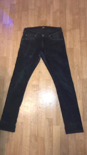 Svarta Lee Luke jeans W31 L32 - Säljer ett par svarta Lee Luke jeans med klassisk femficksdesign och snyggt Lee-läderpatch bak. Jeansen har slim passform och raka ben. Perfekta för dig som gillar en clean och tidlös look. 