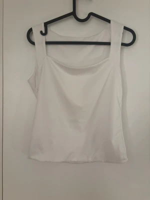 Vit topp🫶🏻 - Snygg vit linnetopp i satin med breda axelband och rak halsringning. Perfekt för att skapa en stilren och fräsch look. Materialet ger en lyxig känsla och passar bra till många olika outfits. Jättefin!🤍