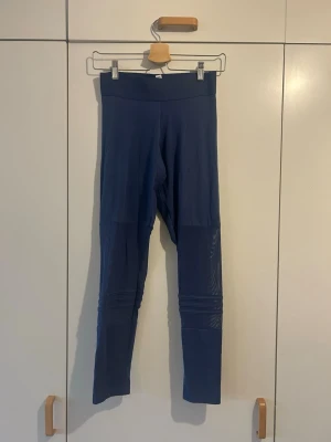 Leggings från Adidas - Snygga blå leggings från Adidas i storlek S. De har meshdetaljer på nedre delen av benen och ribbade sömmar som ger en cool look. Perfekta för träning eller chill. Materialet är mjukt och stretchigt syntet, vilket gör dem riktigt bekväma.