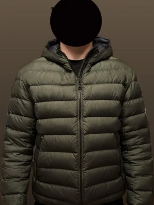 Olivgrön Colmar pufferjacka med huva - Säljer en riktigt fet olivgrön pufferjacka från Colmar med huva och stilren svart dragkedja framtill. Jackan har två sidofickor med dragkedja och Klassiska Colmar-loggan på armen. Perfekt för kalla dagar och riktigt skön passform. Liten skada på insidan av armen, syns ej när man bär jackan! Övrigt topp skick.