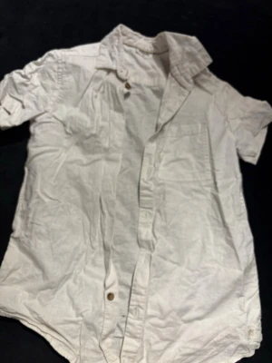 Vit kortärmad skjorta från Kappahl - Fräsch vit skjorta från Kappahl i storlek 158. Skjortan har korta ärmar, klassisk krage och knappar framtill. Tillverkad i mjukt bomullstyg som känns skönt mot huden. Perfekt för varma dagar och enkel att matcha med jeans eller shorts.