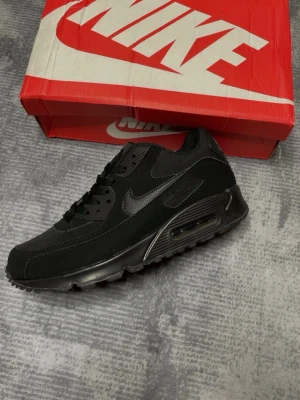 Nike Air Max 90 - Svarta Nike Air Max 90 i storlek 43 (27,5cm), men den passar mer som storlek 42 eftersom att insidans mått visar 27cm. Bra kvalite, samt använt 2-3 gånger men är som ny. Kommer med originella nike lådan. Nike trycket inuti sulan har kommit av lite. Skriv gärna på om du har funderingar, samt så är priset inte satt så hitta på förslag! 💯💬