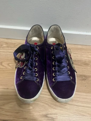 Purple Velvet Sneakers with Satin Laces – Unique & Stylish - Beautiful purple velvet sneakers with satin ribbon laces and side zippers, giving a unique and elegant look. Soft velvet upper, gold-tone eyelets, and a comfortable leather insole. In good used condition – light signs of wear on the soles (see photos), but the velvet and details are still in great shape. Perfect if you want something a bit different from basic sneakers. ✨ Eye-catching ✨ Comfortable ✨ Easy to put on with side zip Great for everyday wear or to elevate an outfit. Details Color: Pur