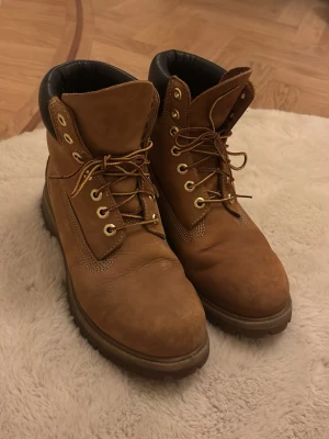 Timberland klassiska bruna boots - Timberland kängor i  brun mocka med snörning. Skorna är perfekta till vintern och är supersköna att använda. Säljs då de blivit för små. Nypris 2400 kr. Kontakta vid fler bilder!