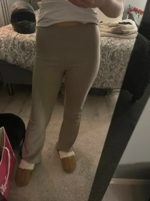 Beige byxor – utsvängda ben – med defekter - Beige byxor i mjukt och bekvämt material med utsvängda ben. Stilrena och lätta att matcha till både vardag och mer uppklädda outfits. Observera att byxorna har några defekter: en tråd har kommit ut samt en liten orange fläck som inte går bort i tvätten. Defekterna är små men finns där.