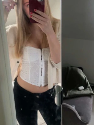 Beige kofta från Lindex med knappar - Supermjuk och mysig beige kofta från Lindex i storlek S. Koftan har rund halsringning, svarta knappar framtill och ribbade muddar. Perfekt att slänga över en topp för en chill look.