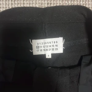 Svarta bootcut-byxor från Maison Margiela - Svarta bootcut jeans från maison margiela i ett kostym-aktigt material. De faller sjukt snyggt på skorna och har en unik med riktigt snygg passform. 