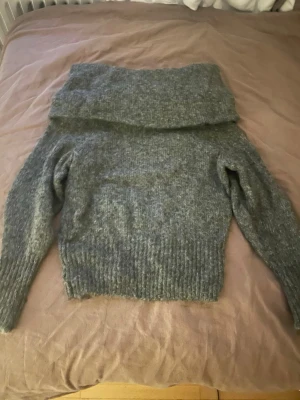 Grå stickad off sholder från H&M - Mysig grå stickad off sholder från H&M i storlek S. Tröjan har långa ärmar och ribbade muddar vid ärmslut och nederkant. Perfekt för kyliga dagar och enkel att styla med jeans eller kjol.