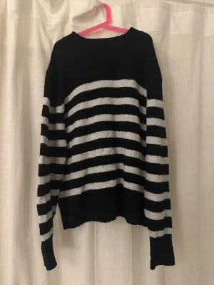 Svart och vit randig stickad tröja H&M - Mysig stickad tröja från H&M i storlek XS. Tröjan har svart botten med breda vita ränder och långärmad modell. Perfekt för att få en chill och stilren look. Materialet är mjukt och ger en skön känsla, passar bra till jeans eller kjol.
