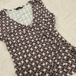 Mönstrad  tröja från Stockh LM - Tröja från Stockh LM med v-ringning och ärmlös design. Tröjan har ett unikt blommigt mönster i brunt och vitt, vilket ger en cool och modern look. 