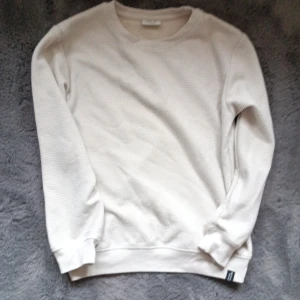 Vit  tröja från Kappahl - Vit långärmad tröja från Kappahl i storlek 134/140. Tröjan har en ribbad struktur och rund halsringning, vilket ger en clean och chill look. Perfekt för dig som gillar enkel stil med lite textur. Materialet känns mjukt och skönt mot huden. Lite fläckar mitt på. Syns knappt.