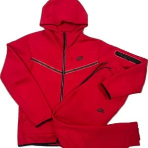 Röd Nike Tech Set - Nike hoodie i stark röd färg med svarta detaljer och dragkedja hela vägen. Tröjan har huva, svarta ränder över bröstet och Nike-logga på bröstet. Matchande byxor med dragsko och logga. Perfekt för chill eller träning. Tröja är storlek S och tröjan är i storlek M 