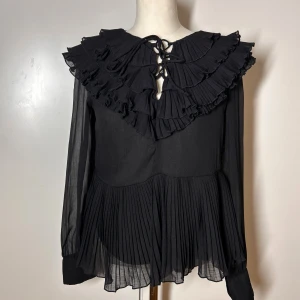 Volang blus  - Blus med volanger från river Island i storlek ”10”. Passar en s. Jag har xs-s och kan ha denna.Köp sker via köp nu, jag postar inom 24h. Kvar tills markerad såld 