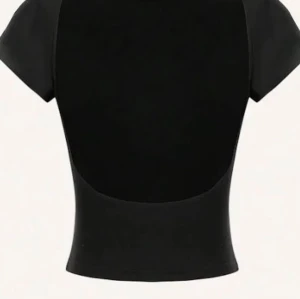 Svart topp med öppen rygg - Svart, enkel topp från Gina Tricot i storlek M. Modellen har korta ärmar och en snygg djup urringning i ryggen. Ändast använd 1-2 gånger!