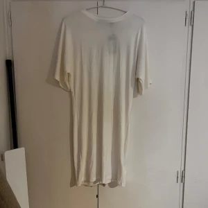 Vit t-shirtklänning från 157 - Vit t-shirtklänning från 157 i storlek S. Klänningen har en enkel och figus sydd form med rund hals och korta ärmar. Tillverkad i mjuk bomull som känns skön mot huden. Perfekt för dig som gillar minimalistisk och clean stil.