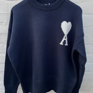 Ami Paris tröja  - Marinblå stickad tröja i storleken M ifrån Ami Paris i helt nytt skick med lappen på. Tröjan är av 100% bomull och har inga täcken på slitage eller fläckar. Har du frågor är det bara att skriva. 