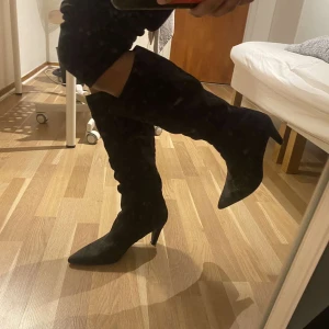 Svarta mockastövlar med klack - Snygga svarta stövlar i mocka med spetsig tå och låg klack. Stövlarna har en elegant och stilren design som passar perfekt till höstens och vinterns outfits. Materialet är mjukt och ger en lyxig känsla. Perfekt för dig som gillar klassiska boots med en modern twist. Skick 9/10 perfekt för kvinnor,