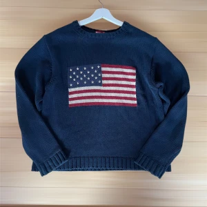 Mörkblå stickad tröja med USA-flagga - Snygg mörkblå stickad tröja med en stor USA-flagga framtill i rött, vitt och blått. Perfekt för dig som gillar snygga och varma tröjor. Just nu sjukt populär och denna är i otroligt bra skick! Pris är inte hugget i sten!🤩