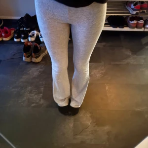 Ljusgrå mjukisbyxor med bootcut - Säljer ett par ljusgrå mjukisbyxor med bootcut. Byxorna har hög midja och är tillverkade i mjukt bomullsmaterial med lite stretch. Passformen är slim upptill och vidare nertill, vilket ger en snygg siluett. Perfekta för en chill och avslappnad stil.