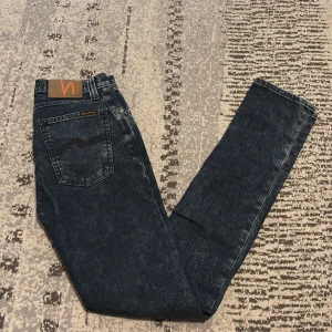Mörkblå skinny jeans från Nudie Jeans - Säljer ett par mörkblå skinny jeans från Nudie Jeans i klassisk femficksmodell. Jeansen har hög midja, smal passform och är tillverkade i slitstarkt denim med snygga slitningar. Perfekta för dig som gillar en tajt och stilren look. Dom är i nyshick och är i jätte bra kvalité. Pris kan diskuteras för en snabb affär, skriv om du har några alls frågor 👍