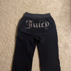 Mörk blåa Juicy Couture mjukisbyxor XXS - Mörk blåa mjukisbyxor från Juicy Couture i velour med glittrande Juicy-text i strass på baksidan och logga framtill. Byxorna har snörning i midjan och raka ben. Perfekta för en chill och trendig look. Använder inte nu för dom or för korta 