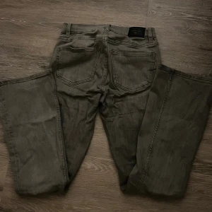 Grå jeans från Gina Tricot, strl S/34 - Snygga grå jeans från Gina Tricot. Klassisk femficksdesign, bootcut och midwaist. Säljer dessa jeans då de aldrig kommer till användning, har bara använts cirka 2 gånger. Passar i längden på mig som är 171cm men börjar bli lite korta. Hör av er vid frågor!🙏🏼(nypris 400kr)