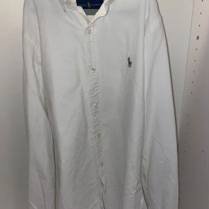 Vit Ralph lauren skjorta - Snygg och stilren Ralph lauren skjorta i färgen vit. Tröjan framhäver en klassisk och elegant stil med den ikoniska logan på bröstet.