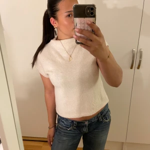 Ljusbeige stickad topp med kort ärm - Säljer en ljusbeige stickad topp med korta ärmar och rund hals. Modellen är croppad och har en enkel, stilren design utan mönster eller detaljer. Lite liten i storleken.