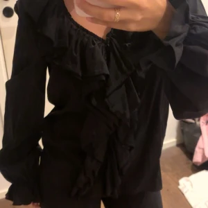 Svart volangblus ZARA - Säljer denna otroligt fina blusen som knappt är använd. Jag tycker att den sitter något för löst på mig trots att det är en XS. 