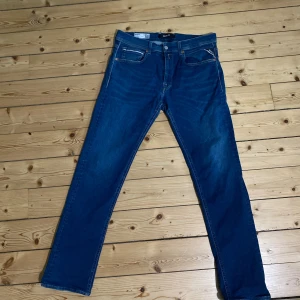 Blå Replay jeans Grover - Säljer ett par klassiska blå jeans från Replay med raka ben och normal passform.  Modell Grover och storlek 32 32. Jeansen har fem fickor, snygga detaljer på bakfickorna och är tillverkade i slitstarkt denimtyg. Perfekta för dig som gillar en tidlös och clean look🔥