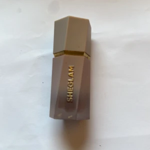 Bronzer  - Bronzer SHEGLAM i en stilren nude-färgad hylsa med gulddetalj. Hylsan har en modern, kantig form och känns lyxig att hålla i handen. Perfekt för dig som gillar neutrala toner och vill ha ett trendigt tillskott i sminkväskan.